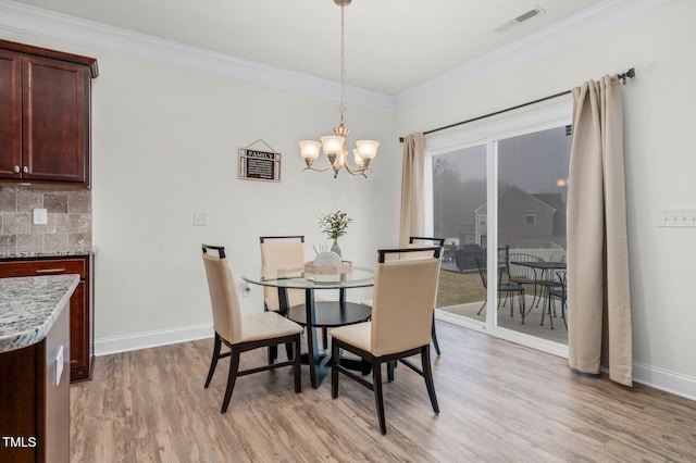dining space with light wood-style flooring, a chandelier, crown molding, and baseboards