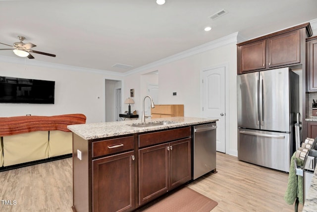 kitchen featuring appliances with stainless steel finishes, a sink, light wood-type flooring, crown molding, and dark brown cabinets