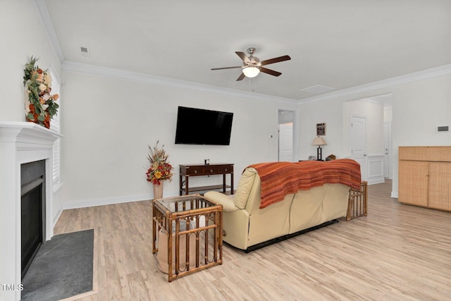 living room with ceiling fan, light wood-type flooring, ornamental molding, a fireplace with flush hearth, and baseboards