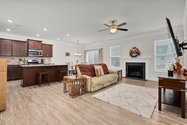living area with ornamental molding, ceiling fan, light wood-style flooring, a fireplace with flush hearth, and recessed lighting