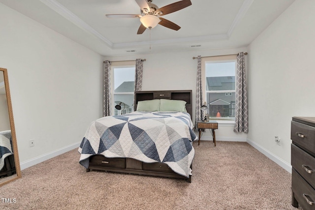 bedroom with a raised ceiling, multiple windows, carpet floors, and crown molding