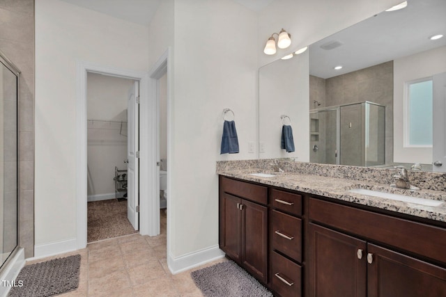 bathroom featuring a shower stall, double vanity, and baseboards
