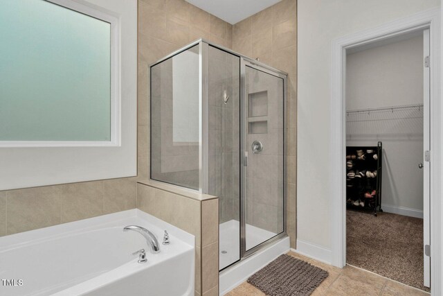 bathroom with a stall shower, a bath, tile patterned floors, and a spacious closet