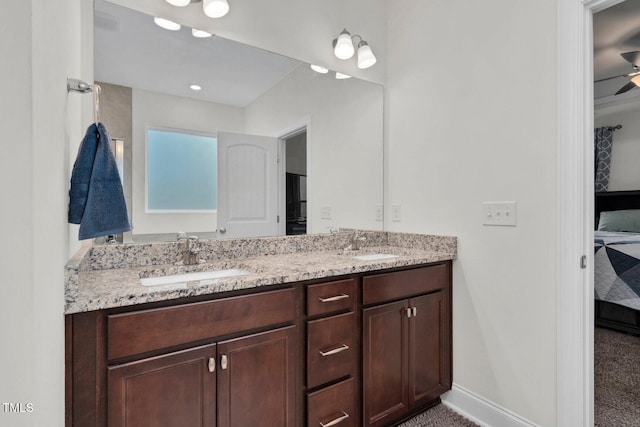 full bathroom with ensuite bathroom, double vanity, a ceiling fan, and baseboards