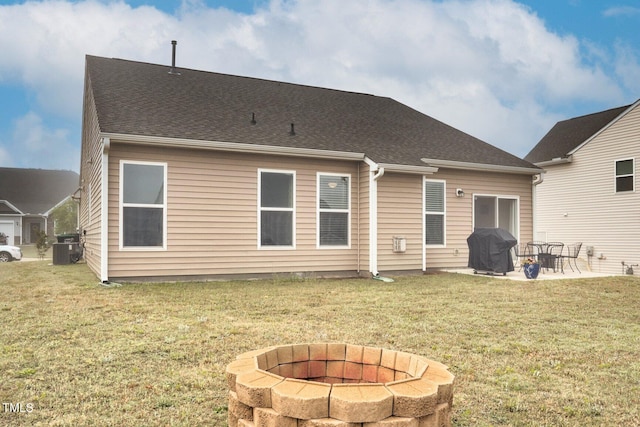rear view of property featuring a fire pit, a patio, a yard, and central AC