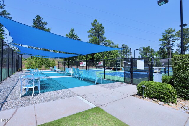 view of property's community featuring a tennis court and fence