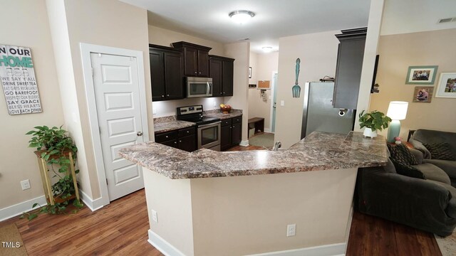 65 Wood Green Dr, Wendell, NC 27591 - kitchen featuring a peninsula, wood finished floors, stainless steel appliances, baseboards, and light stone countertops