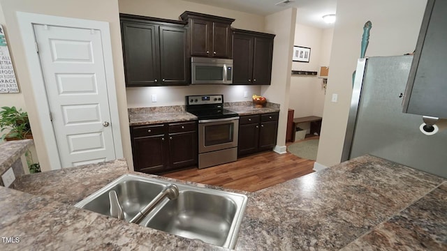 65 Wood Green Dr, Wendell, NC 27591 - kitchen featuring dark brown cabinets, wood finished floors, a sink, stainless steel appliances, and visible vents