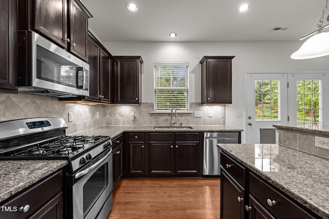 kitchen with stainless steel appliances, a sink, light stone countertops, light wood-style flooring, and recessed lighting