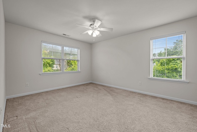 carpeted spare room featuring healthy amount of natural light, ceiling fan, and baseboards