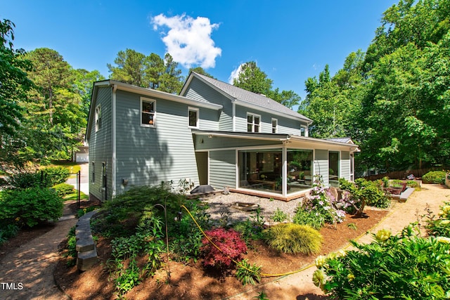 back of property with fence, a vegetable garden, and a sunroom