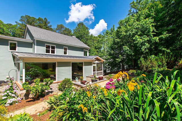 back of property with a standing seam roof, a sunroom, and metal roof