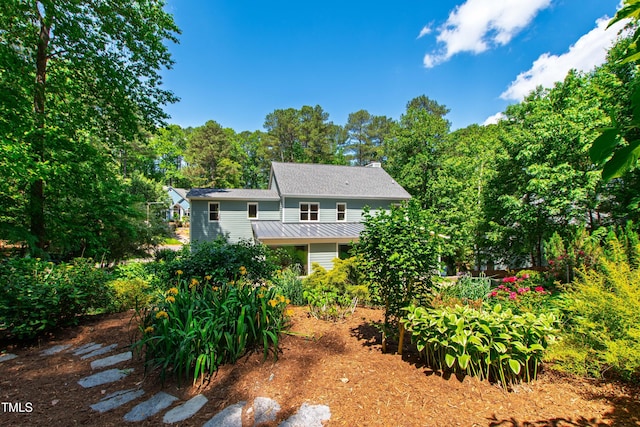 rear view of property featuring a chimney, a standing seam roof, and metal roof