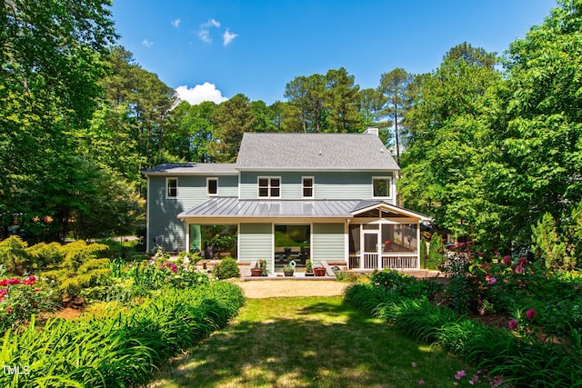 back of property with a sunroom, a patio, a yard, a standing seam roof, and metal roof