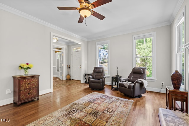 sitting room with hardwood / wood-style flooring, crown molding, a ceiling fan, and baseboards