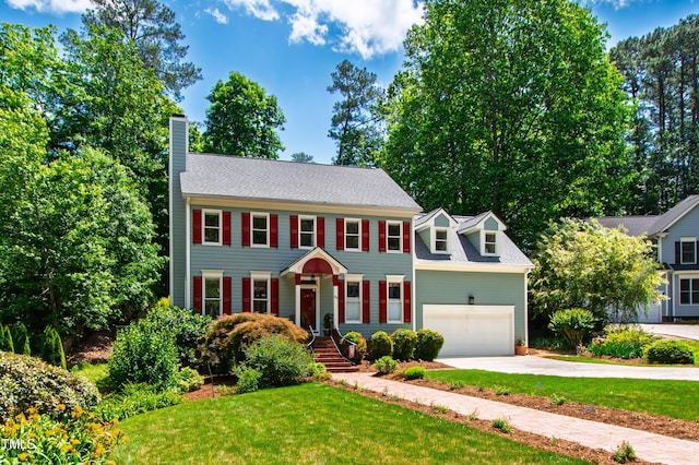 colonial inspired home with a chimney, concrete driveway, a front yard, and a garage