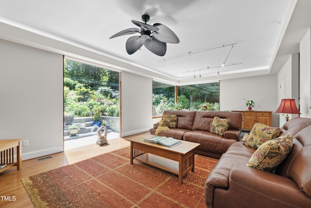 living area with track lighting, light wood-type flooring, ceiling fan, and baseboards
