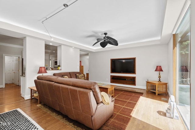 living area with dark wood finished floors, baseboards, ceiling fan, and a tray ceiling