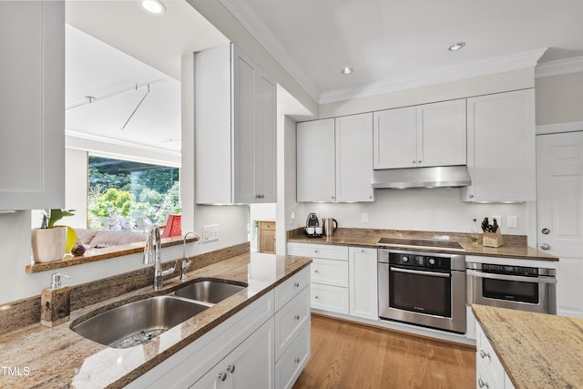 kitchen with oven, under cabinet range hood, a sink, black electric cooktop, and ornamental molding