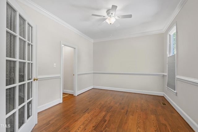 empty room with wood finished floors, ornamental molding, ceiling fan, and baseboards