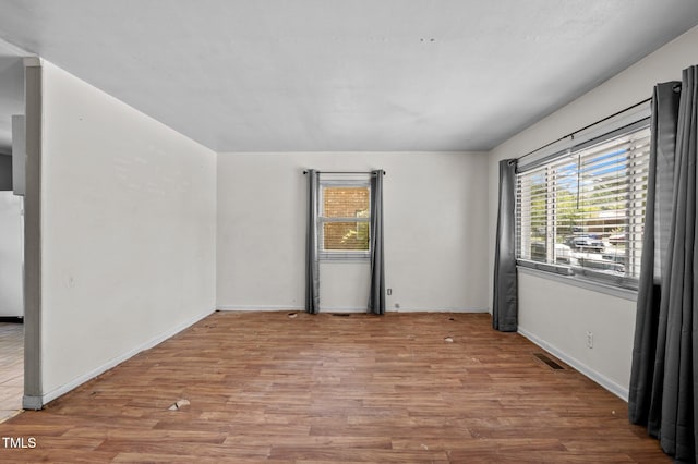 unfurnished room featuring wood finished floors, plenty of natural light, and baseboards