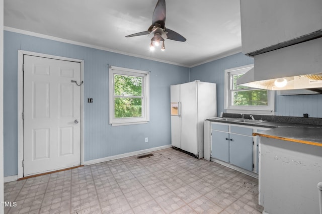 kitchen with a sink, white fridge with ice dispenser, ornamental molding, dark countertops, and ceiling fan