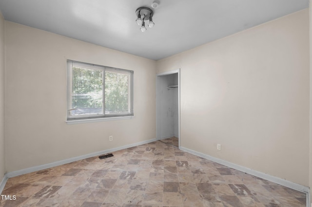 unfurnished bedroom with stone finish flooring, baseboards, and a closet