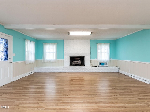 unfurnished living room with baseboard heating, plenty of natural light, light wood finished floors, wainscoting, and visible vents