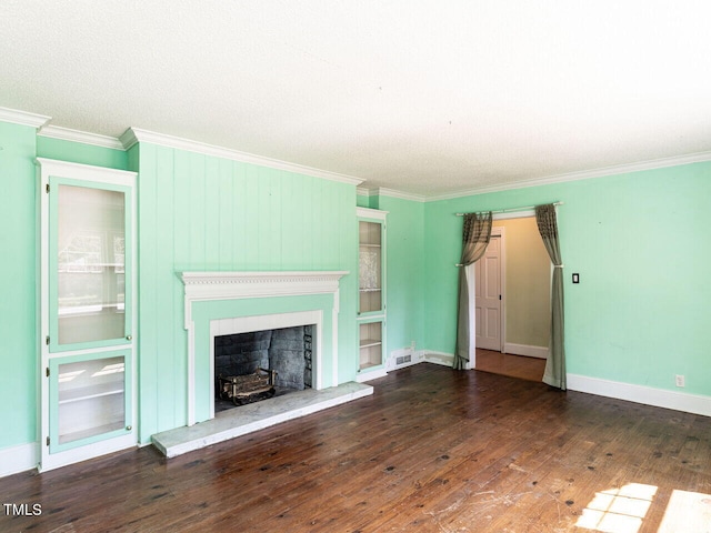 unfurnished living room featuring visible vents, a fireplace with raised hearth, ornamental molding, and hardwood / wood-style flooring