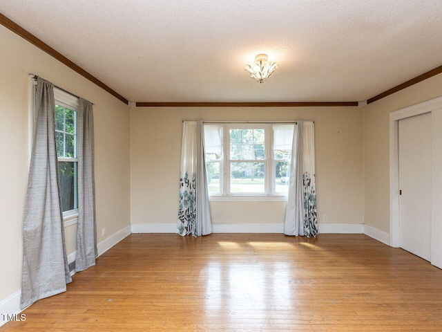 unfurnished room featuring crown molding, baseboards, and light wood-style floors
