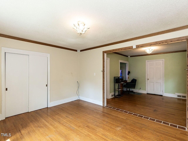 interior space with crown molding, light wood-style floors, visible vents, and a closet