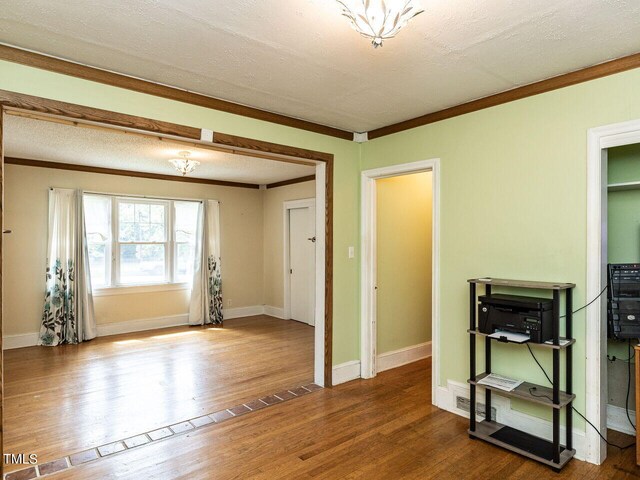 unfurnished room with crown molding, baseboards, and wood finished floors