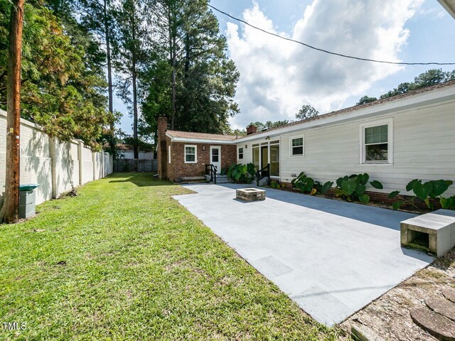 back of house with a patio area, a fire pit, a fenced backyard, a chimney, and a lawn