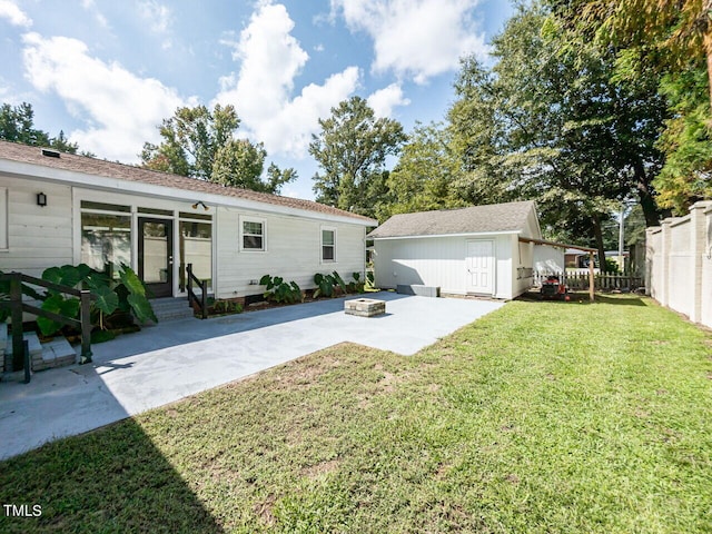 view of front of home with fence, a patio, an outdoor structure, an outdoor fire pit, and a front yard