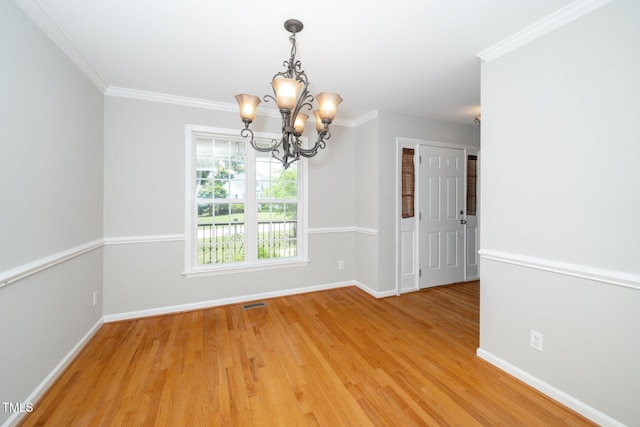 empty room featuring a chandelier, baseboards, light wood-type flooring, and crown molding