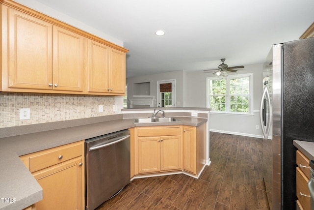 kitchen with a sink, appliances with stainless steel finishes, a peninsula, dark wood finished floors, and tasteful backsplash