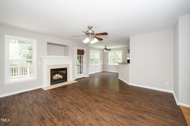 unfurnished living room with a fireplace with flush hearth, dark wood-style flooring, baseboards, and ceiling fan