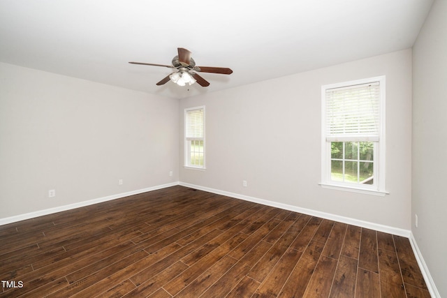 spare room featuring dark wood finished floors, healthy amount of natural light, baseboards, and ceiling fan