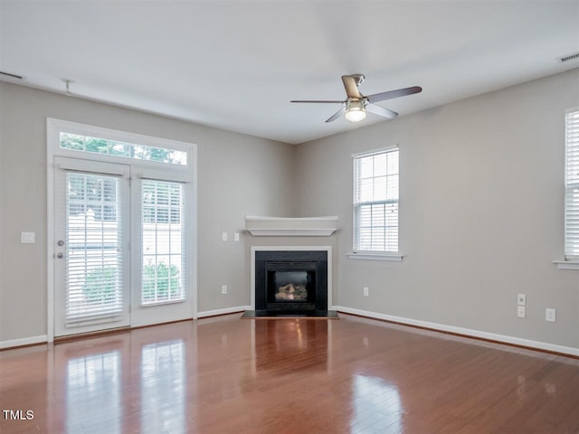 8219 Martello Ln, Raleigh, NC 27613 - unfurnished living room featuring baseboards, a ceiling fan, a glass covered fireplace, and wood finished floors