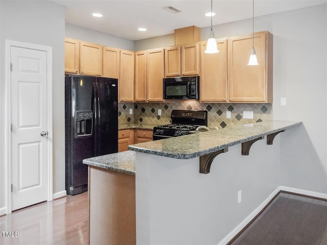 8219 Martello Ln, Raleigh, NC 27613 - kitchen with a peninsula, black appliances, a kitchen bar, light brown cabinets, and baseboards