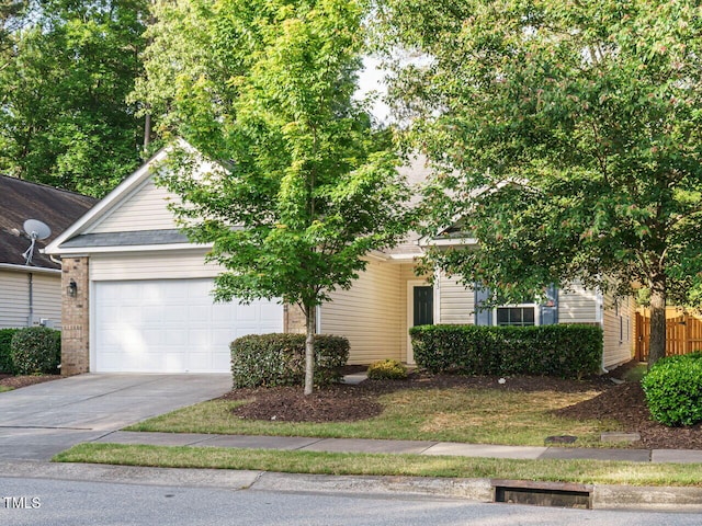 view of property hidden behind natural elements featuring driveway and an attached garage