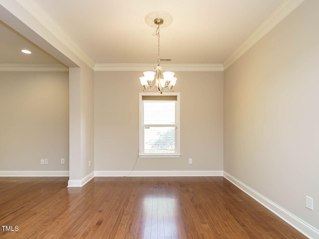 empty room featuring a chandelier, crown molding, dark wood-type flooring, and baseboards