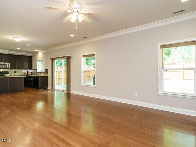 unfurnished living room with ornamental molding, baseboards, wood finished floors, ceiling fan, and recessed lighting