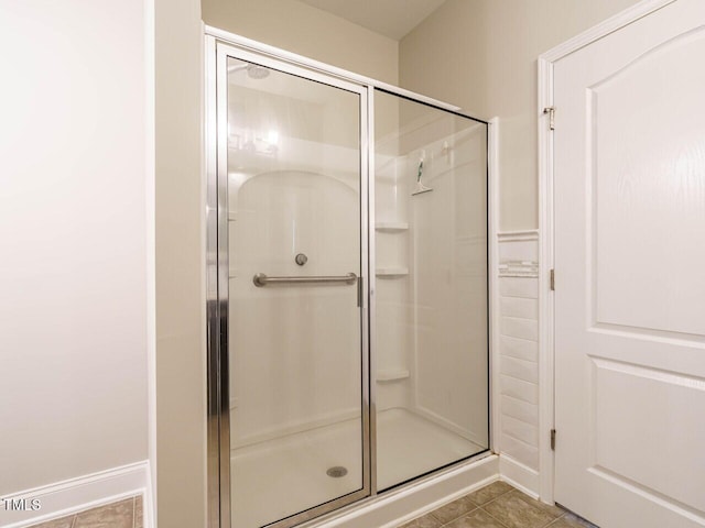 full bathroom with a stall shower, baseboards, and tile patterned flooring