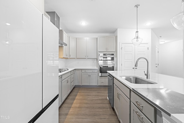 kitchen with gray cabinetry, dark wood-style flooring, hanging light fixtures, a sink, and stainless steel appliances