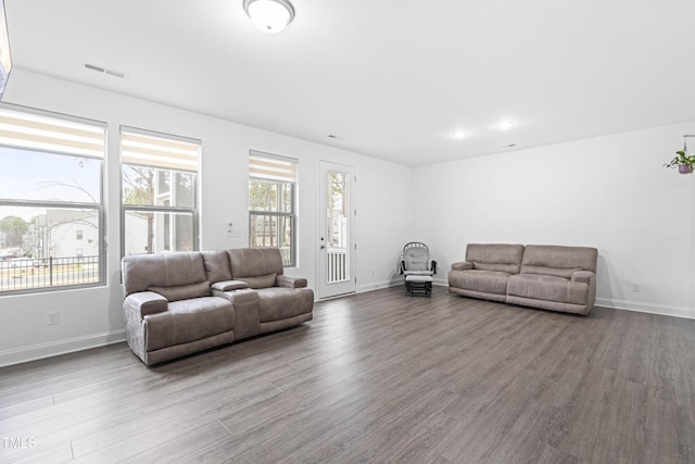 living area featuring visible vents, wood finished floors, and baseboards