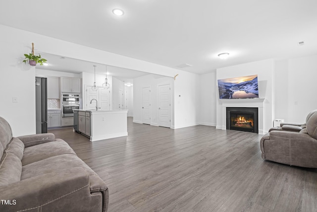 living room with dark wood finished floors, a lit fireplace, baseboards, and recessed lighting