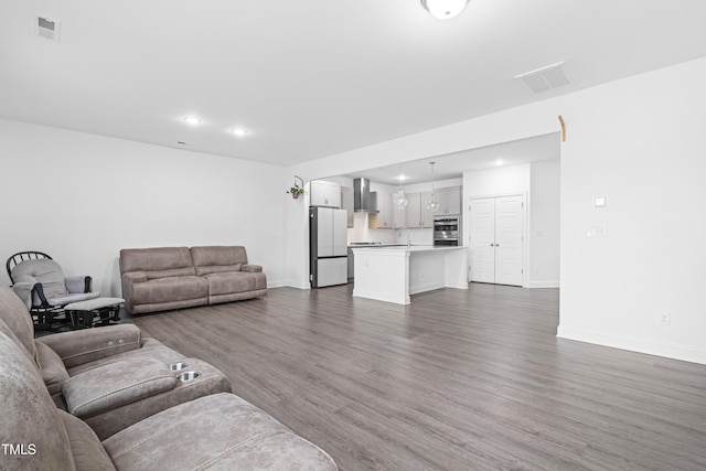 living area featuring baseboards, dark wood-style floors, visible vents, and recessed lighting