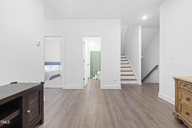 unfurnished living room with attic access, wood finished floors, and baseboards