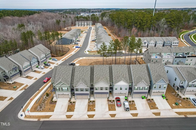 drone / aerial view featuring a wooded view and a residential view